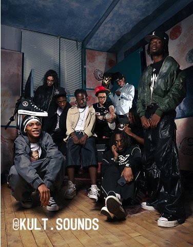 The image shows a group of nine people posing together in a room with artistic wall decorations and wooden flooring. They are dressed in casual streetwear, including hats, jackets, and sneakers, with the text &ldquo;@KULT.SOUNDS&rdquo; displayed at the bottom left corner.
