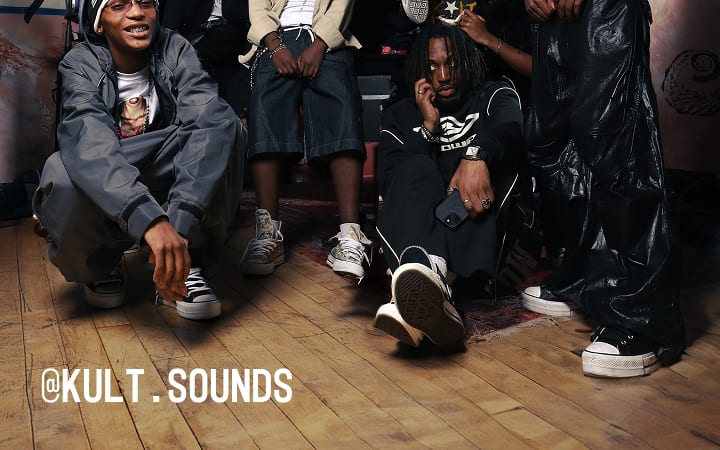 The image shows a group of people dressed in casual, street-style clothing posing indoors on a wooden floor. The text &ldquo;@KULT.SOUNDS&rdquo; is prominently displayed in white at the bottom left corner of the image.