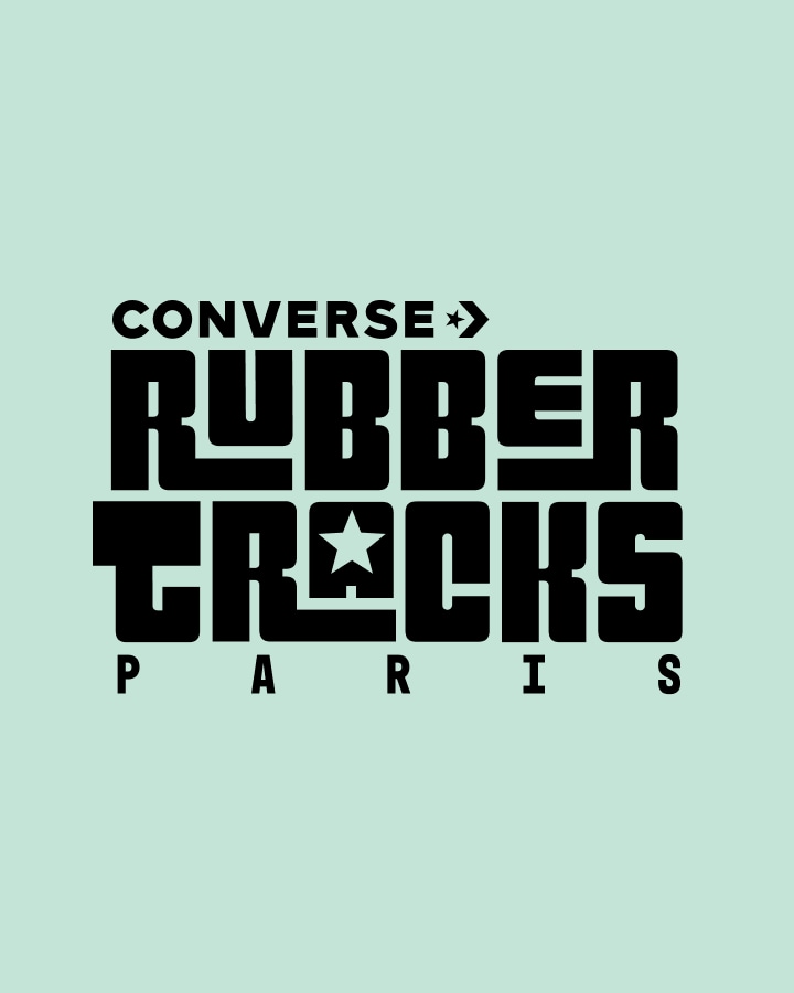 The image features a bold, stylized black text logo on a light green background that reads &ldquo;CONVERSE RUBBER TRACKS PARIS.&rdquo; The design incorporates star symbols within the words and uses a blocky, geometric font style.