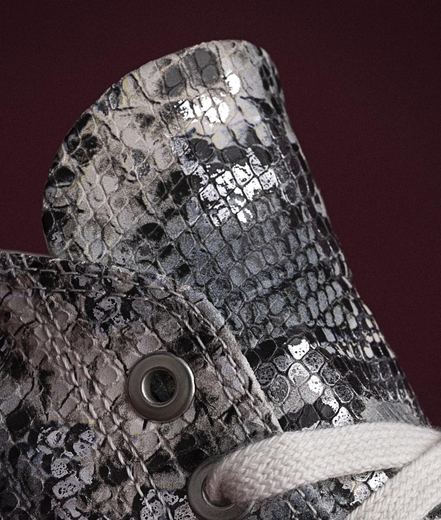 A person is sitting on the floor with their legs bent and arms reaching toward their feet, wearing white sneakers and socks. Their head is blurred in motion, obscuring their face.