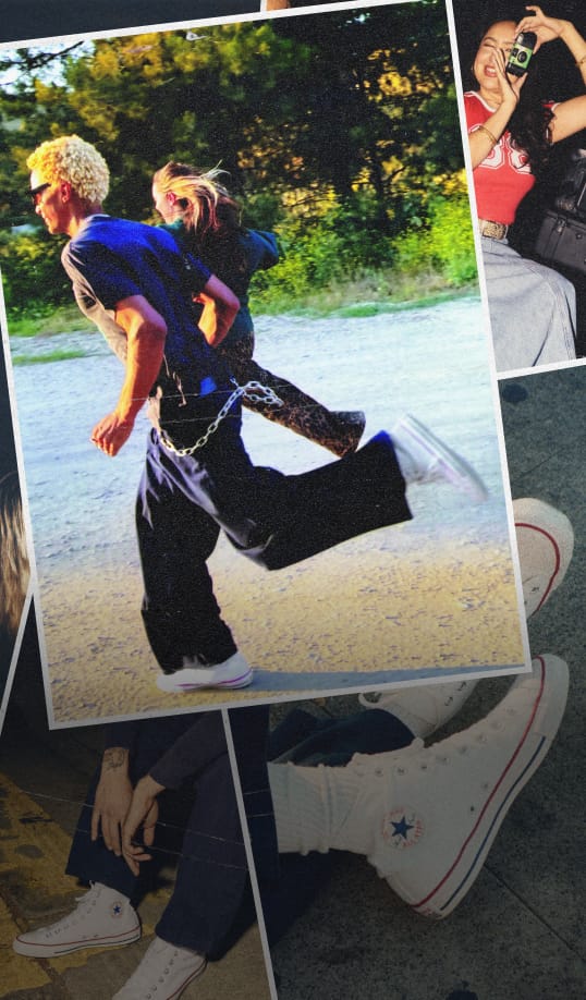 One person has short curly blonde hair and wears a dark blue shirt and wide-legged pants with white sneakers; they also have a chain accessory hanging from their waist. The other person has long hair tied back and wears leopard print pants. 