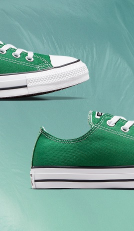 The image shows two close-up views of a green canvas sneaker with white laces and a white rubber sole. The shoe features detailed stitching, metal eyelets, and a black stripe along the sole against a muted teal background.