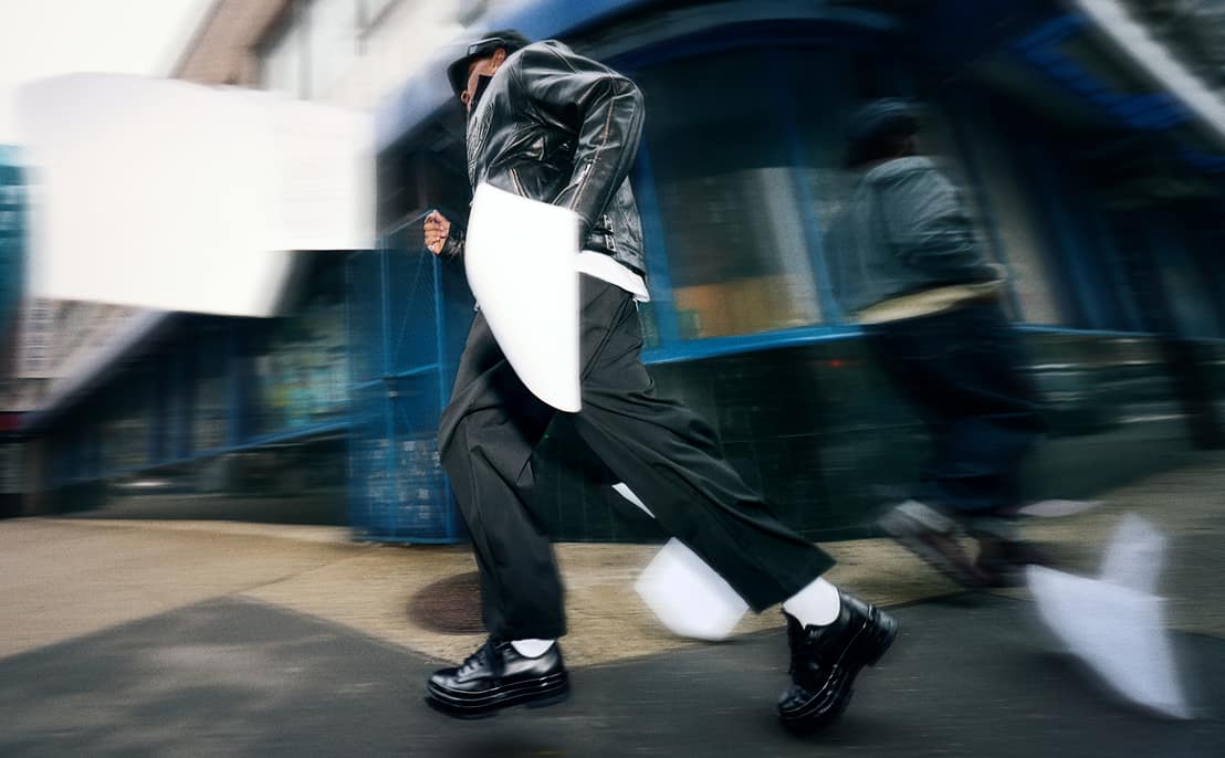 Photo of man running in urban setting in black Converse Loafer shoes