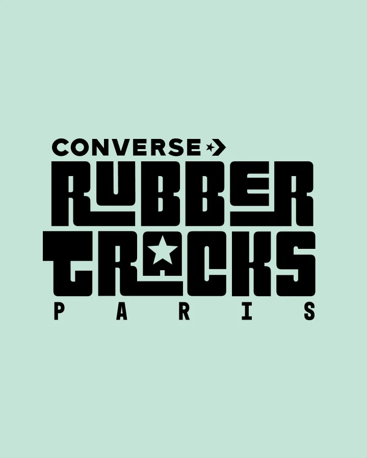 The image features a bold, stylized black text logo on a light green background that reads &ldquo;CONVERSE RUBBER TRACKS PARIS.&rdquo; The design incorporates star symbols within the words and uses a blocky, geometric font style.