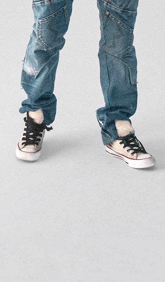 The image shows faded blue jeans and off-white Converse sneakers. The look is clean, casual, and minimal.