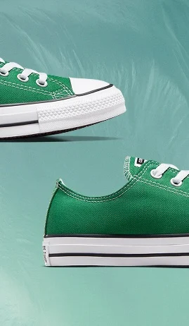 The image shows two close-up views of a green canvas sneaker with white laces and a white rubber sole. The shoe features detailed stitching, metal eyelets, and a black stripe along the sole against a muted teal background.
