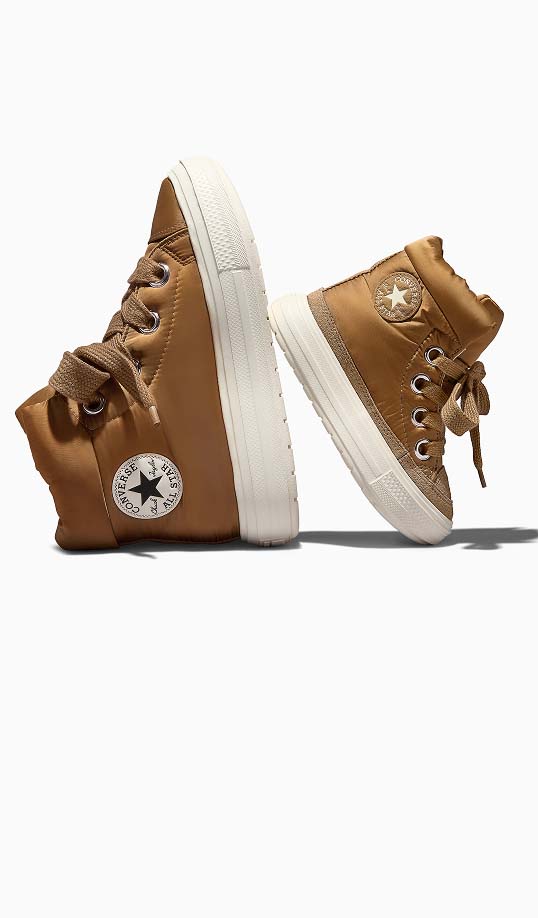 A pair of brown high-top Converse boots with white rubber soles and visible circular All Star logos on the ankles. The padded nylon uppers feature thick laces and metal eyelets, shown side-by-side on a white background.