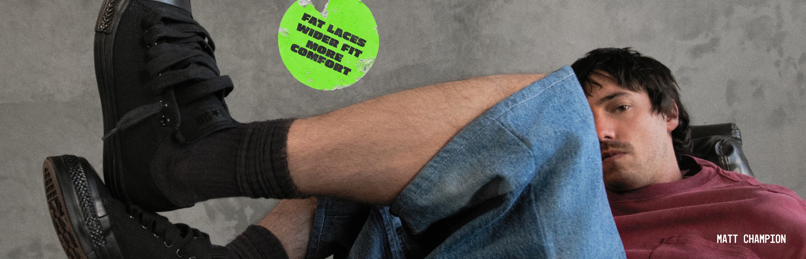 Photo of UK Rapper, Knucks, sitting on a leather couch wearing Chuck Taylor Throwback shoes