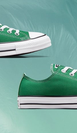 The image shows two close-up views of a green canvas sneaker with white laces and a white rubber sole. The shoe features detailed stitching, metal eyelets, and a black stripe along the sole against a muted teal background.